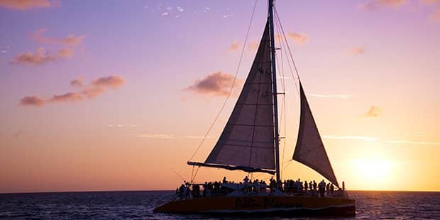 Purple sunset behind tourists on a sailboat