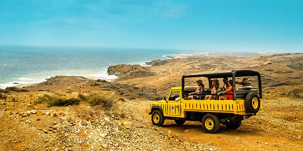 Yellow land rover on dirt road looking at ocean