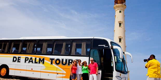 Family taking photo in front of De Palm Tours bus