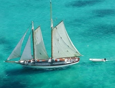 Old sailboat sailing through blue ocean water