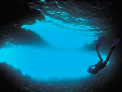 Tourist snorkeling in cave underwater