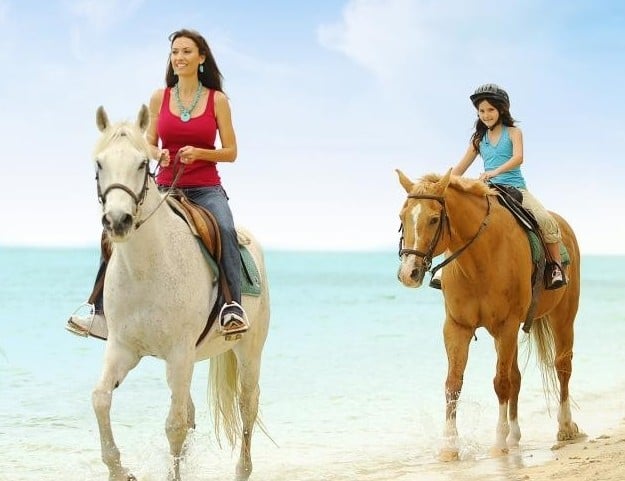 Two people on horses on the beach