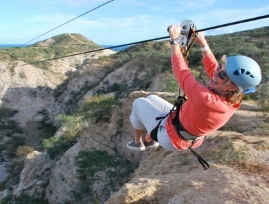 Woman zip-lining through rocks