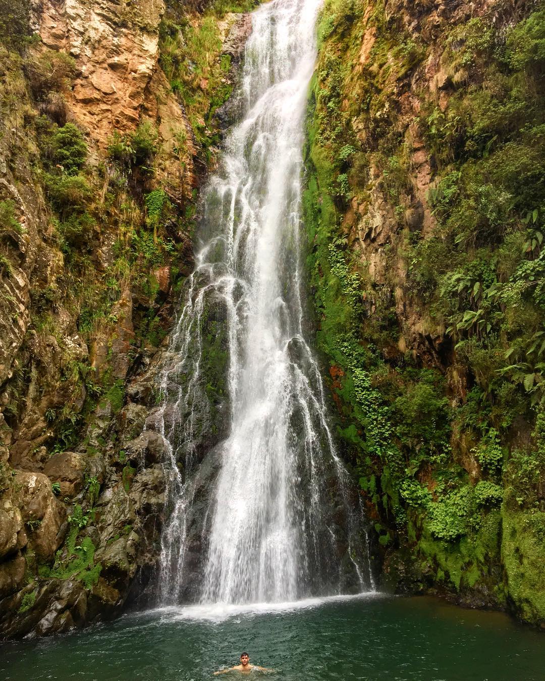 Man swimming at bottom of waterfall