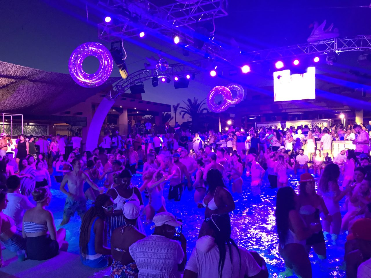 Pool filled with people dancing at night.