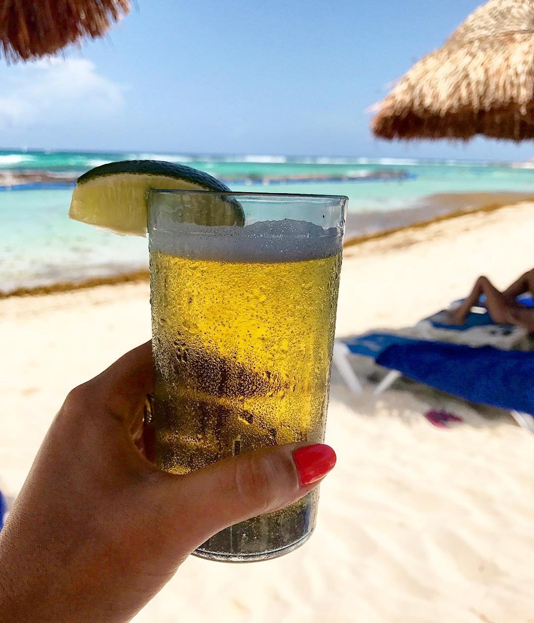 Draft beer in hand on resort beach. 