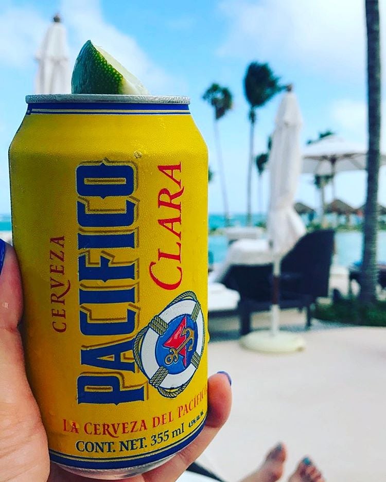 Person holding Pacifico beer with pool in the background. 