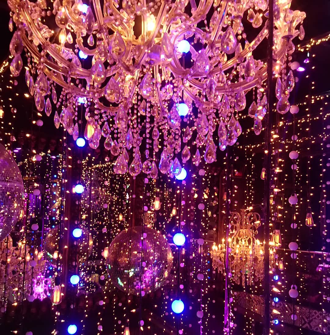 Room with chandelier, disco ball and hanging lights. 