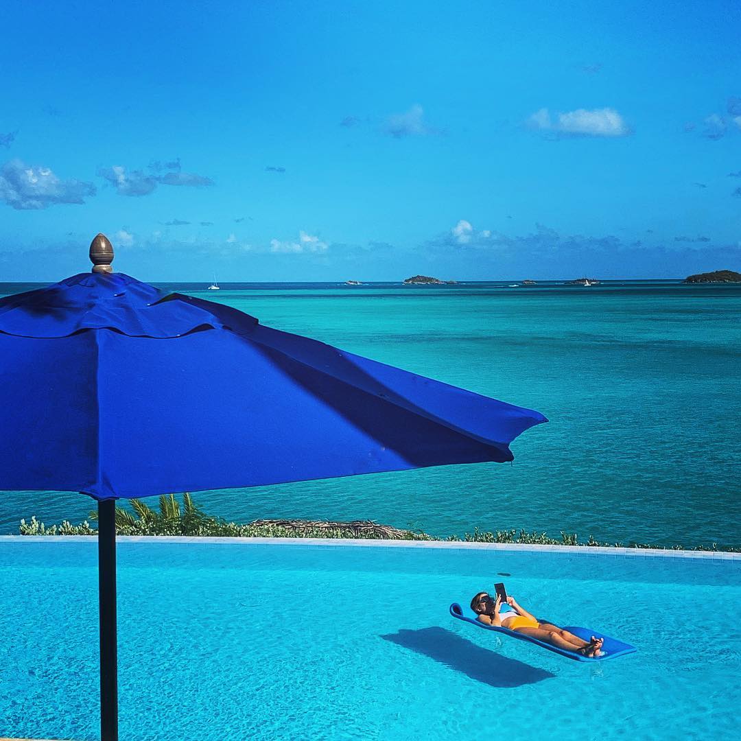 Girl laying in pool with ocean view.