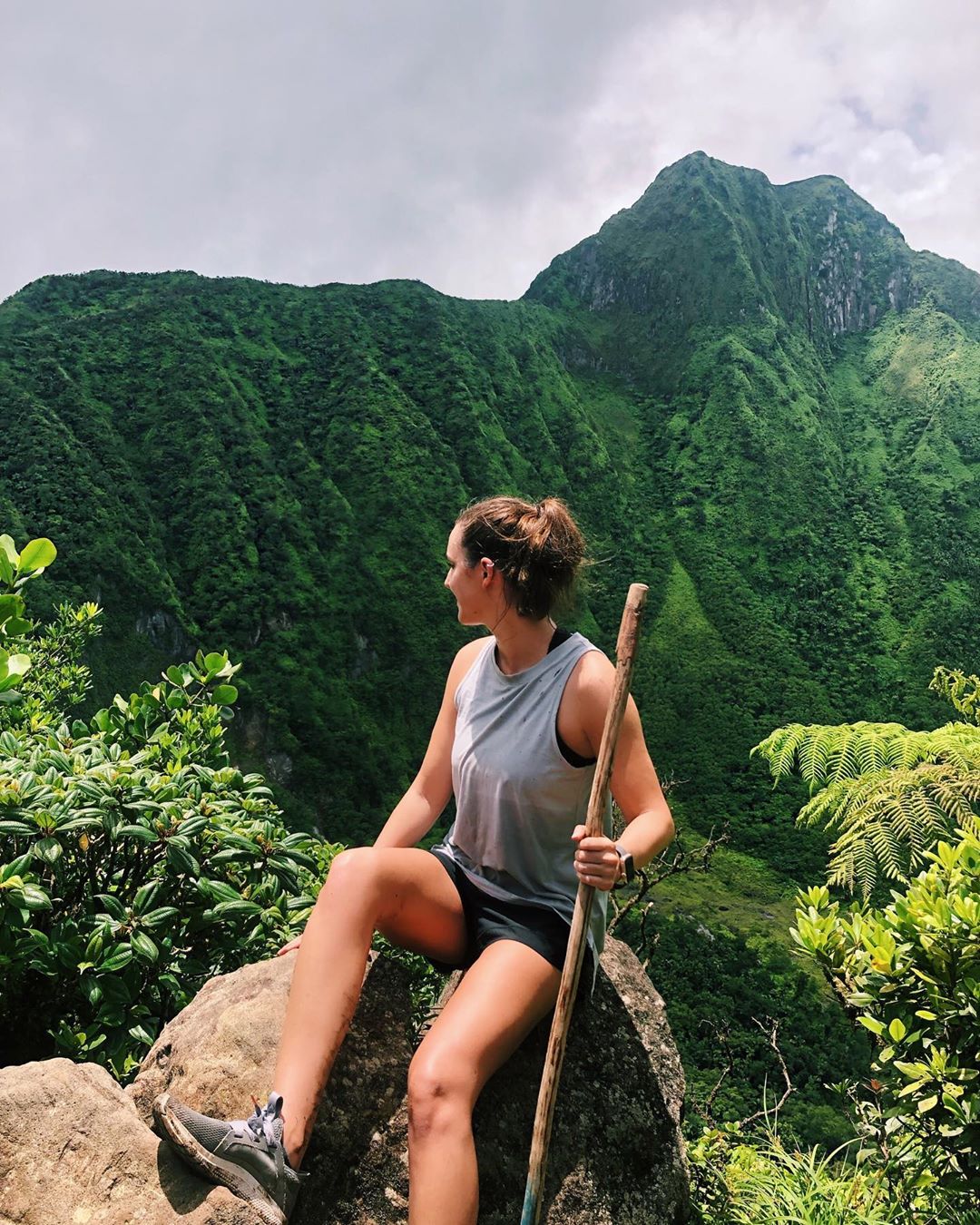 Girl with walking stick at top of the mountain.