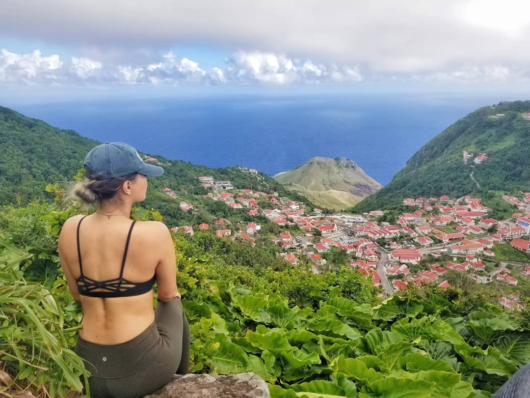 Girl sitting on rock overlooking the town of Saba and the ocean.