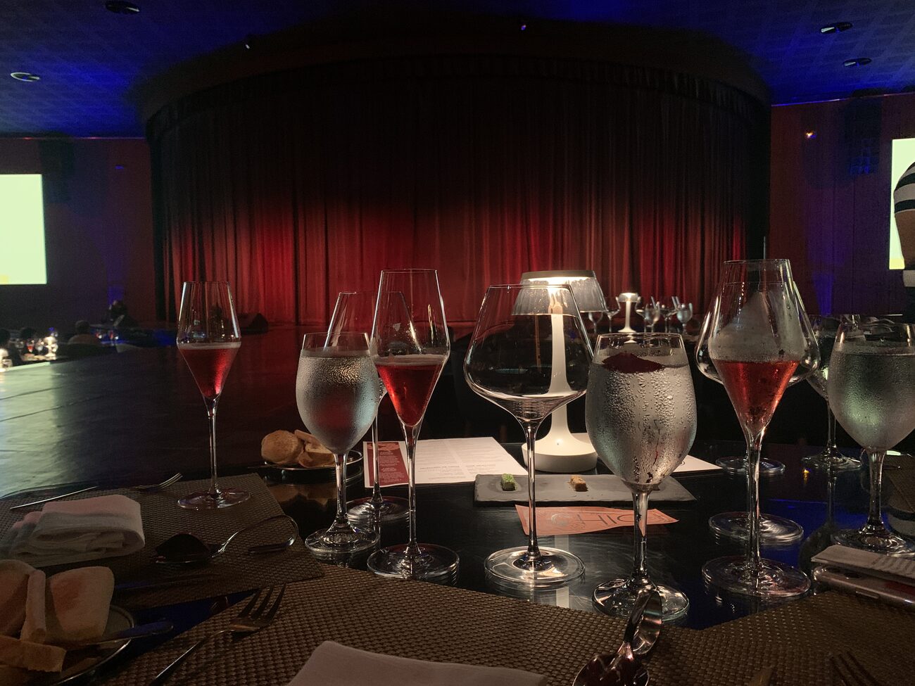 Wine glasses on table with stage in background.